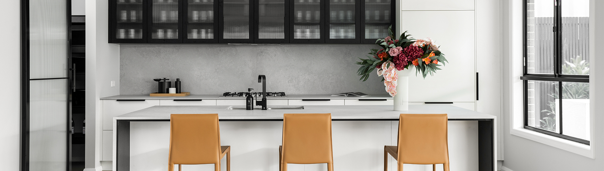 white kitchen with black and fluted glass top cupbards and breakfast stools